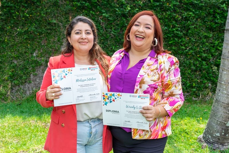 two women smiling holding certificates