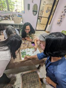 women crowded around a box of gemstones